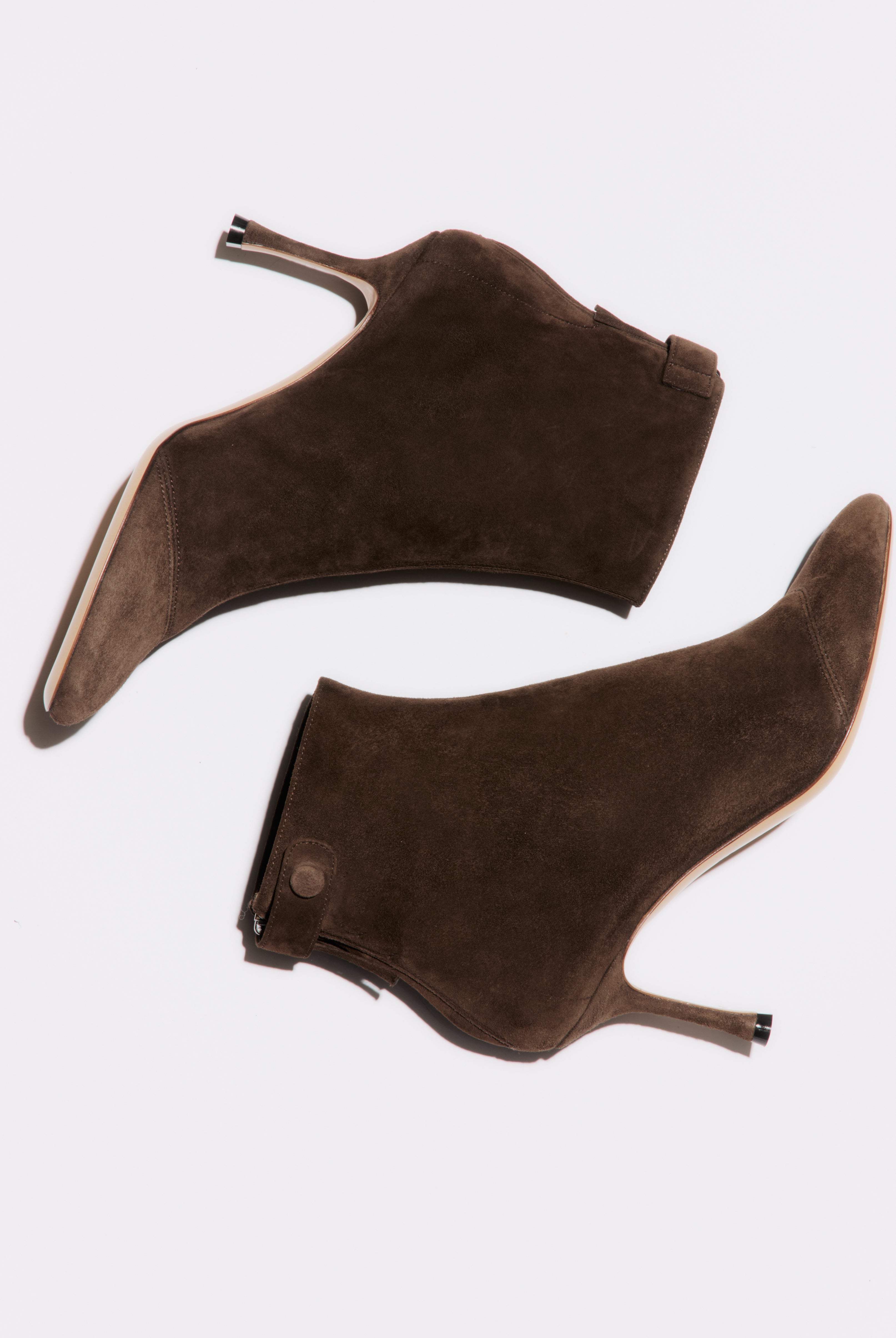 Pair of brown suede high-heeled shoes on a white background