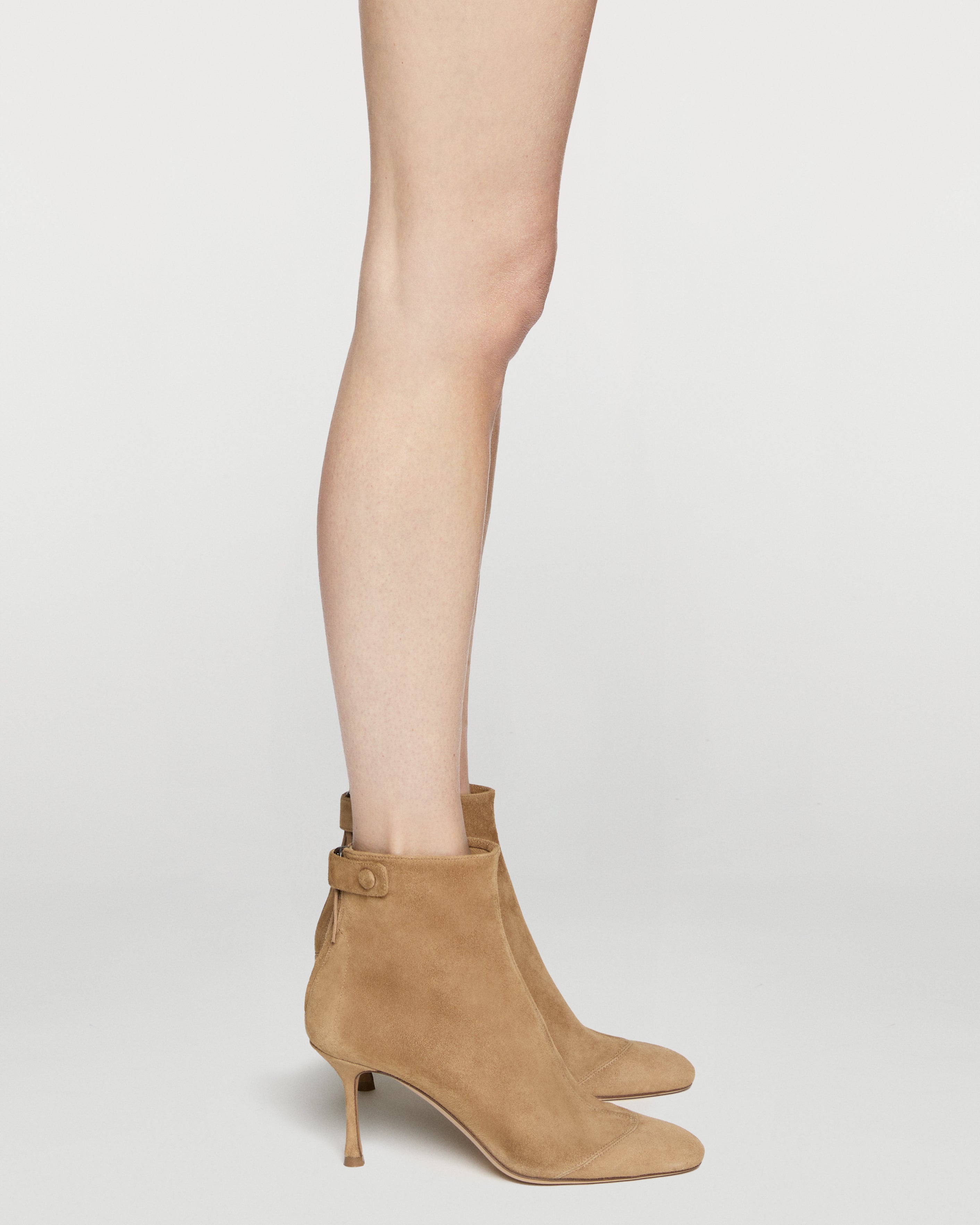 Tan ankle boots worn with a neutral background