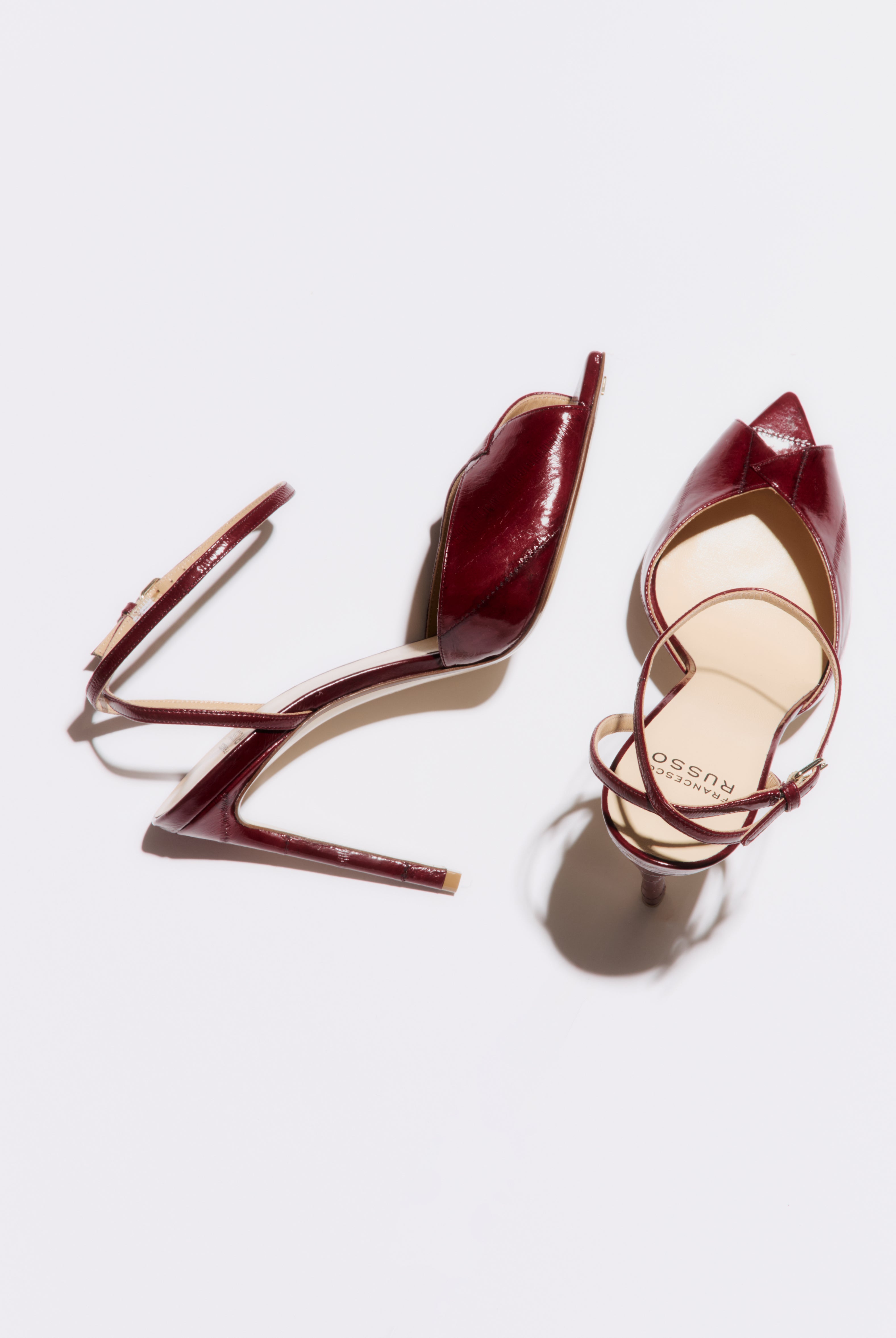 Pair of burgundy high-heeled shoes on a light gray background