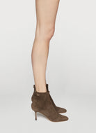 Brown suede ankle boots worn with a neutral background