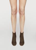 Brown ankle boots worn with beige tights on a white background