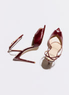Pair of burgundy high-heeled shoes on a light gray background