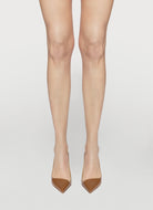 Beige high-heeled shoes worn with sheer beige stockings on a light gray background
