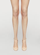 Beige tights worn with beige shoes on a light gray background