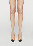 Beige high-heeled shoes worn with sheer beige stockings on a white background