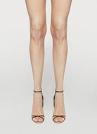 Transparent high-heeled shoes worn with sheer leggings on a white background